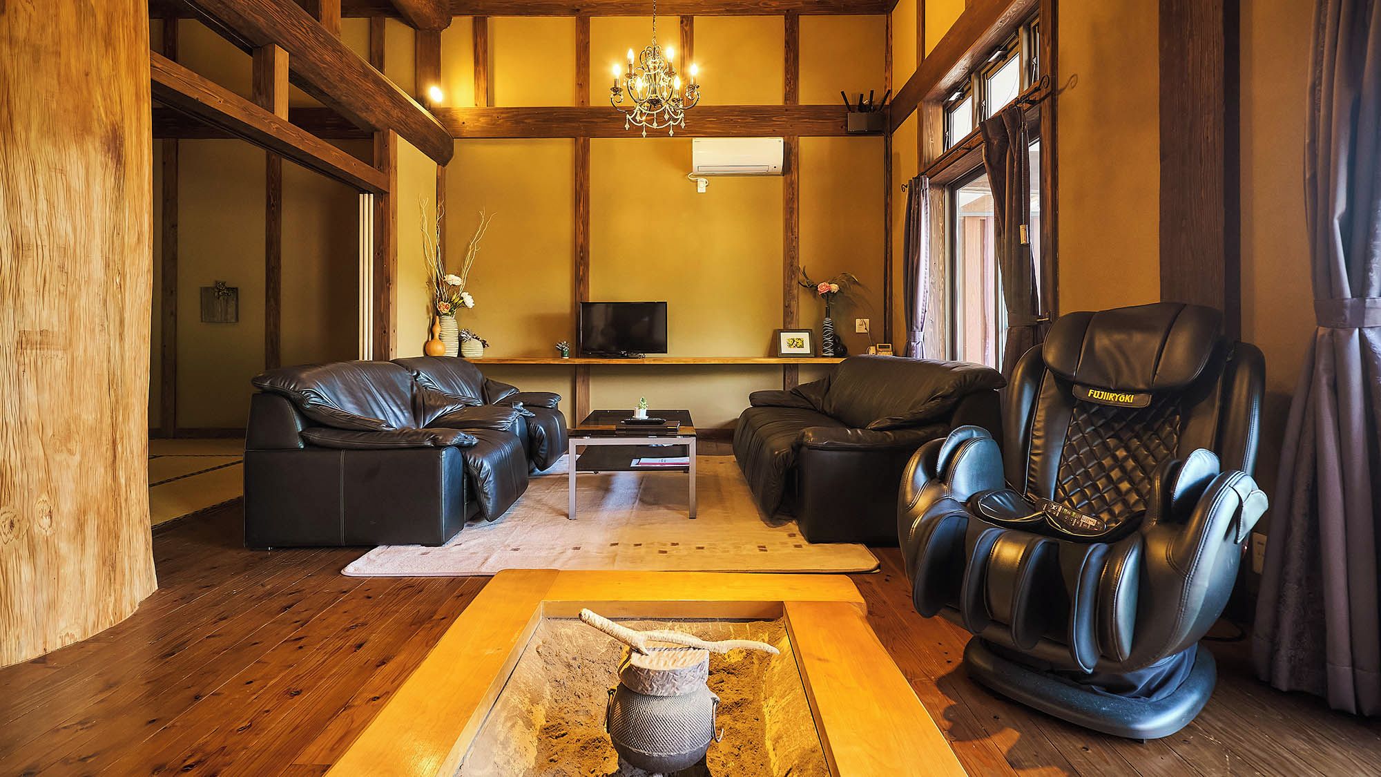 Una sala de estar acogedora con sofás de cuero, un sillón de masaje, una mesa de centro de madera y un televisor.
