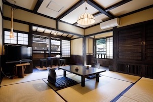 Una habitación tradicional japonesa con suelo de tatami, una mesita baja y un televisor.