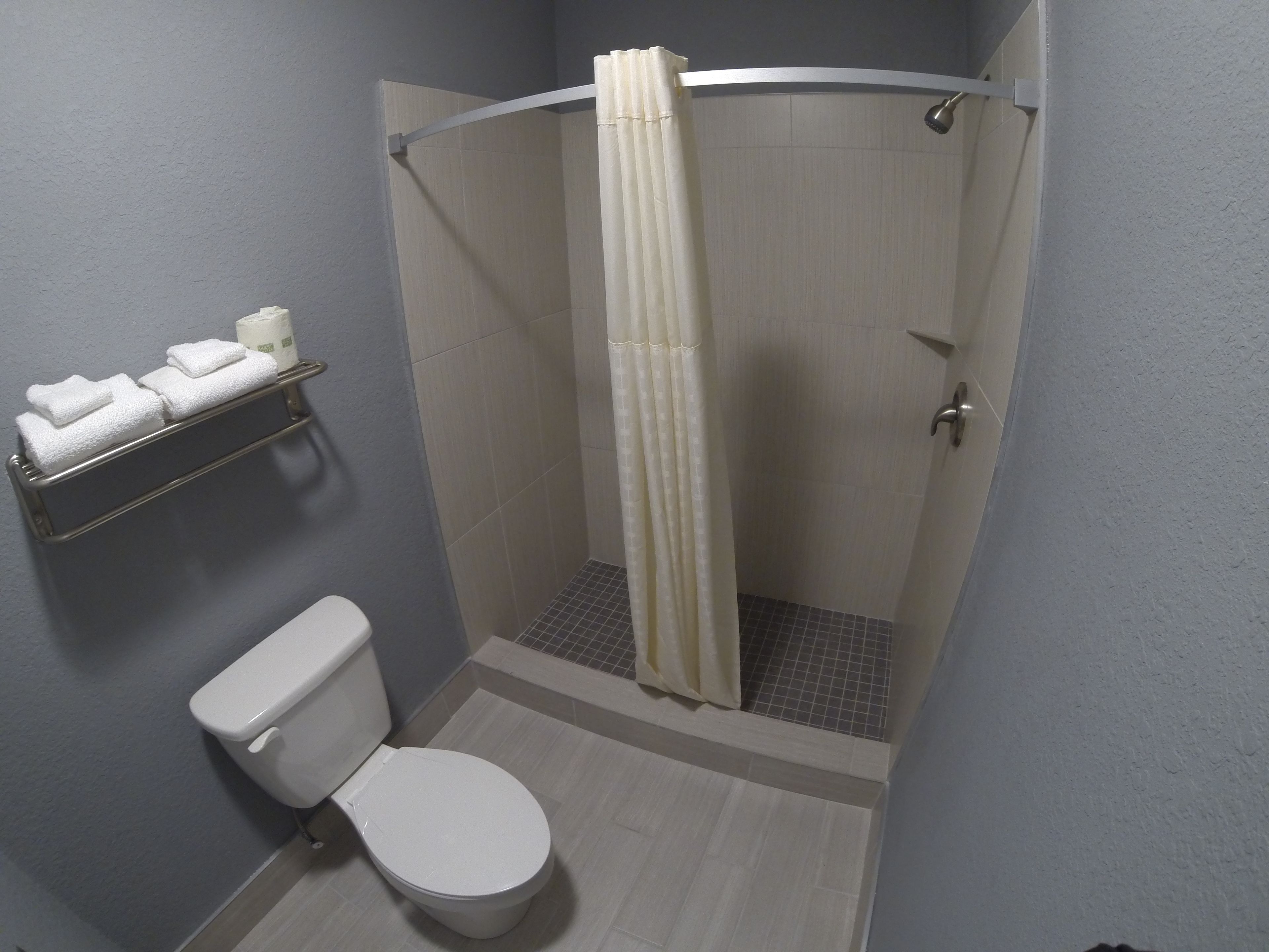 Un baño pequeño con inodoro, ducha con cortina y toallero con toallas dobladas.