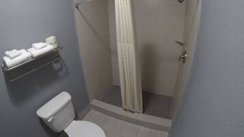 Un baño pequeño con inodoro, ducha con cortina y toallero con toallas dobladas.