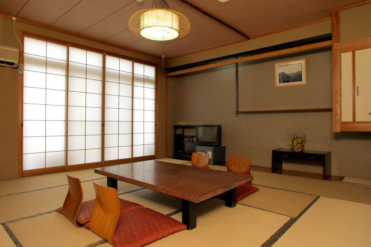 Una habitación japonesa tradicional con suelo de tatami, una mesa baja y puertas correderas.