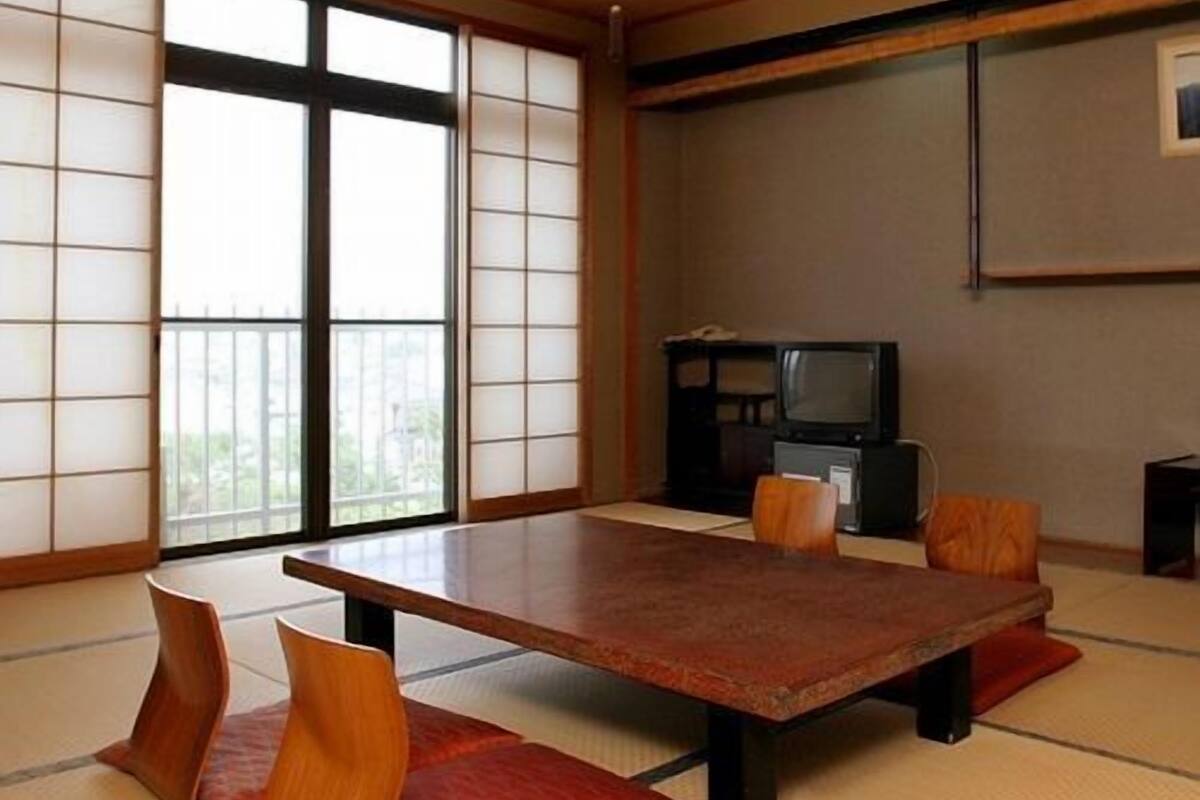Una habitación japonesa tradicional con suelo de tatami, una mesa baja y cojines.