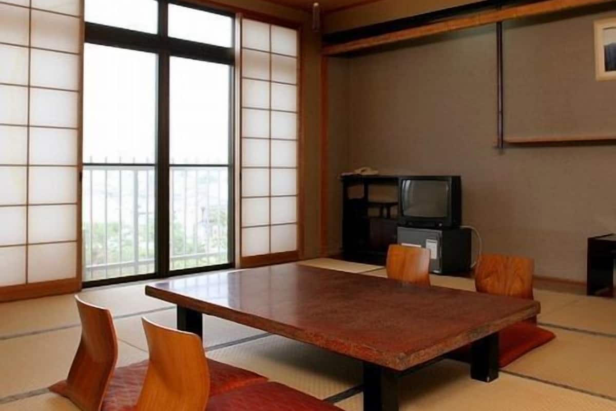 A traditional Japanese room with tatami flooring, a low table, and cushions.