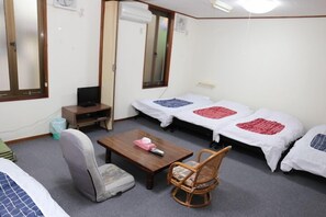 A room with two beds, a small desk, a chair, a television, and a window.
