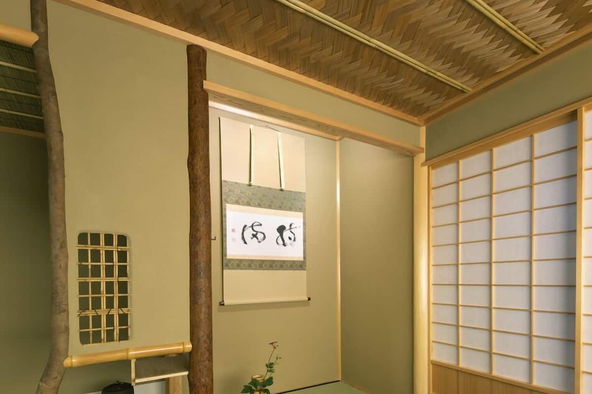 A traditional Japanese room with tatami flooring, a shoji screen, and a hanging scroll.