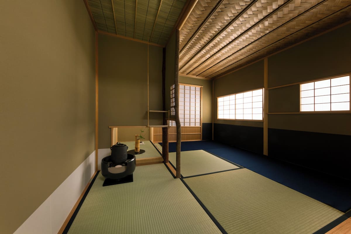 A traditional Japanese room with tatami flooring, sliding doors, and a low ceiling.
