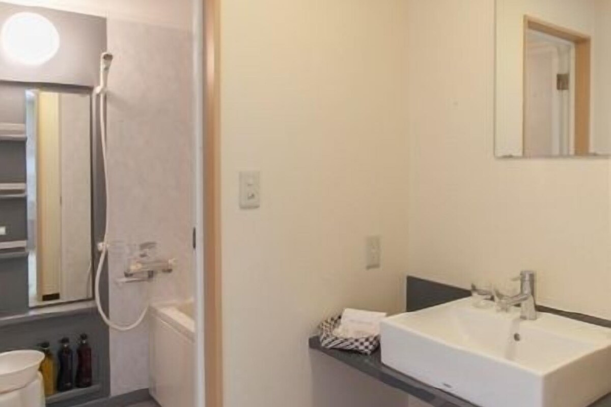 A bathroom with a sink, mirror, and shower.