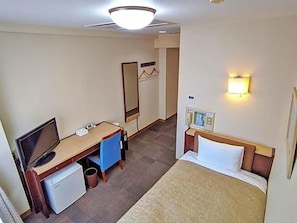 Habitación de hotel con cama, escritorio con computadora, refrigerador pequeño, espejo y teléfono en la pared.