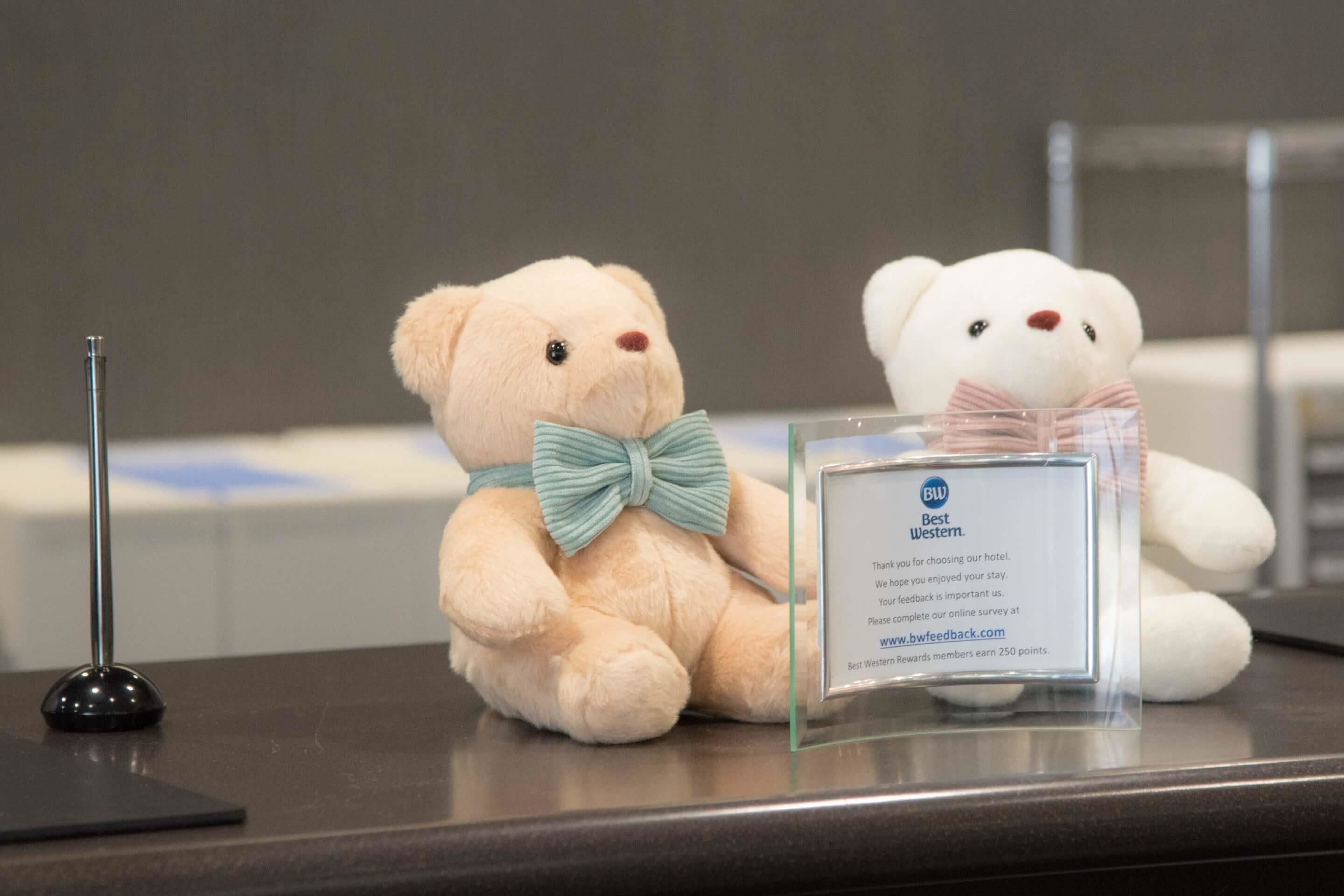 Twee pluchen teddyberen op een toonbank met een bordje waarop 'Best Western' staat.