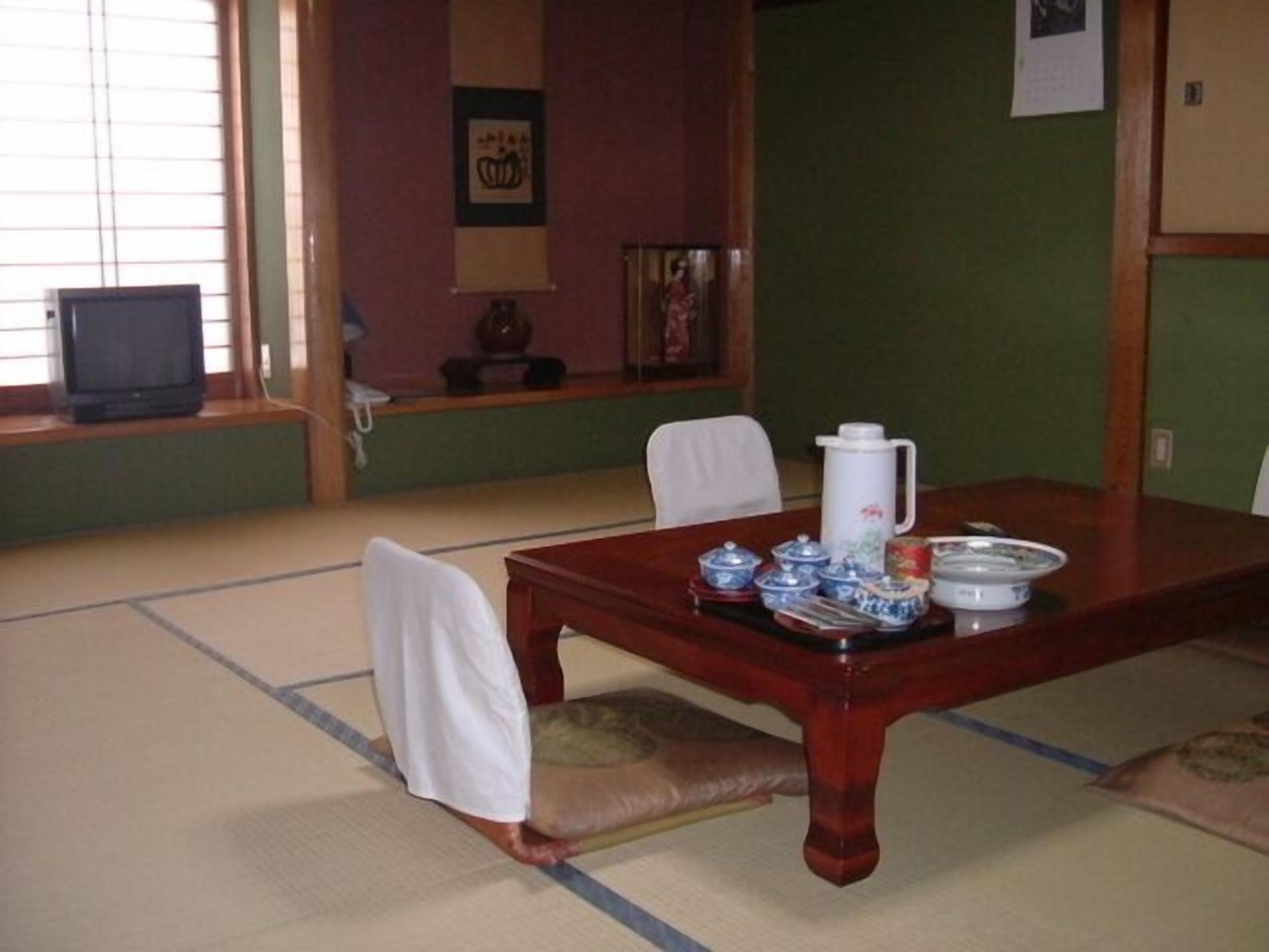 A tatami mat room with a wooden table, chairs, and traditional Japanese decor.
