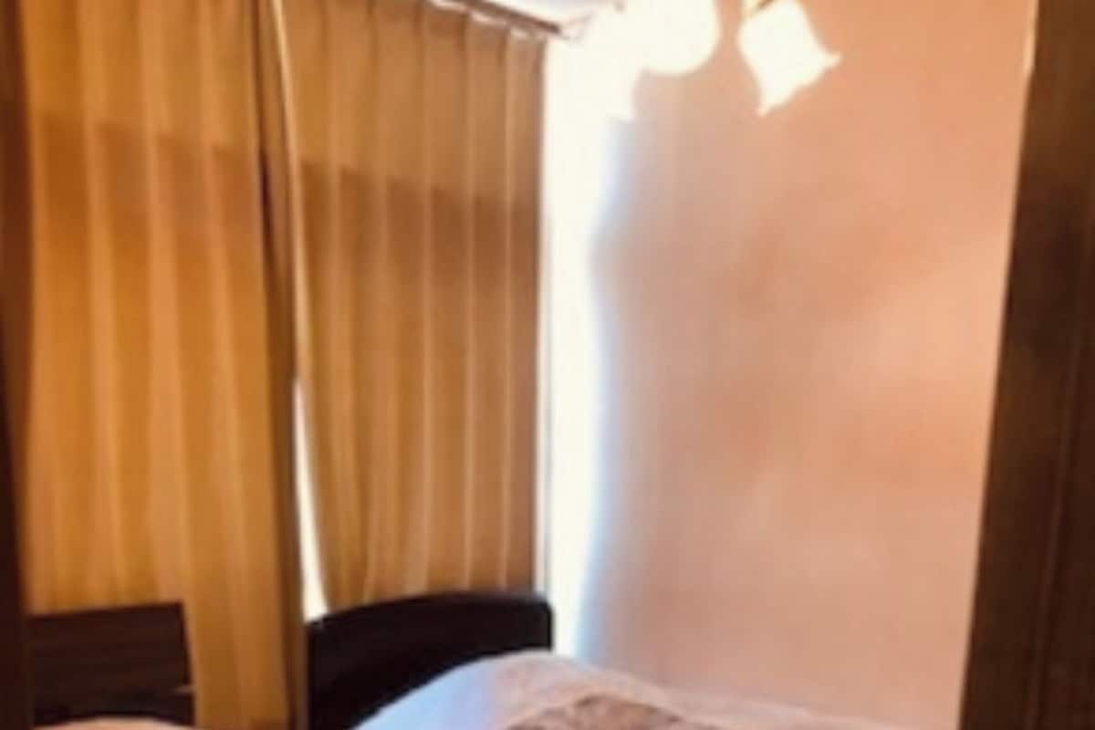 A room with two single beds, wooden headboards, and a window with curtains.