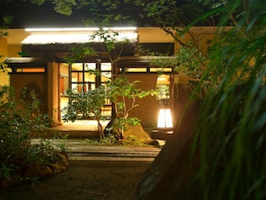 A traditional Japanese building with a thatched roof, surrounded by greenery and a stone pathway. - Yufuin Yumeguri Hotel Sankouen (Yufu)