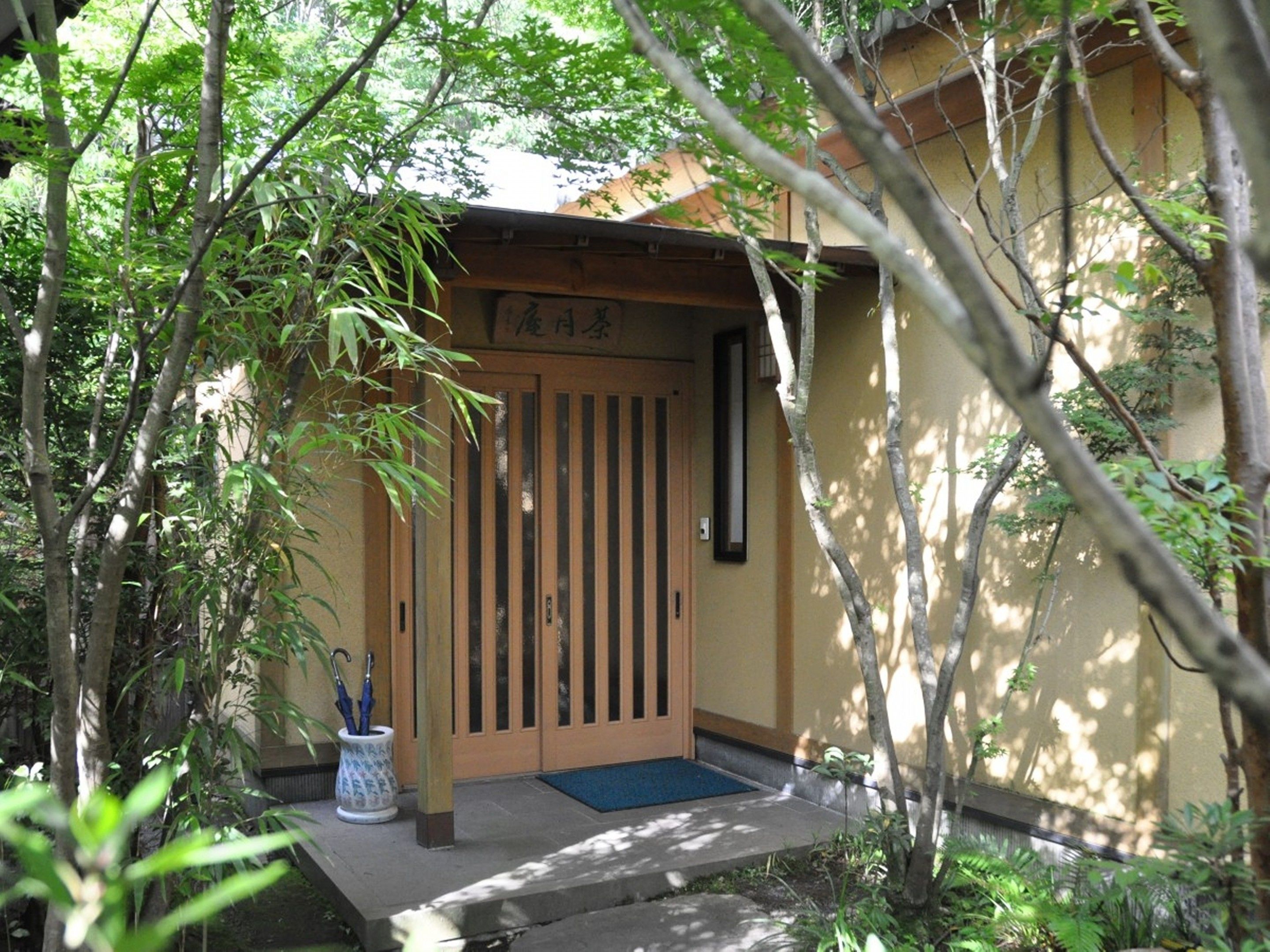 A traditional Japanese gate with a wooden door and a small porch area.