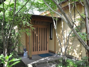 A traditional Japanese gate with a wooden door and a small porch area.