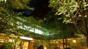 Un edificio tradicional japonés con un corredor cubierto y follaje circundante.