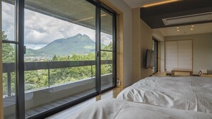 Un dormitorio con un amplio ventanal que ofrece vistas a una montaña y vegetación.