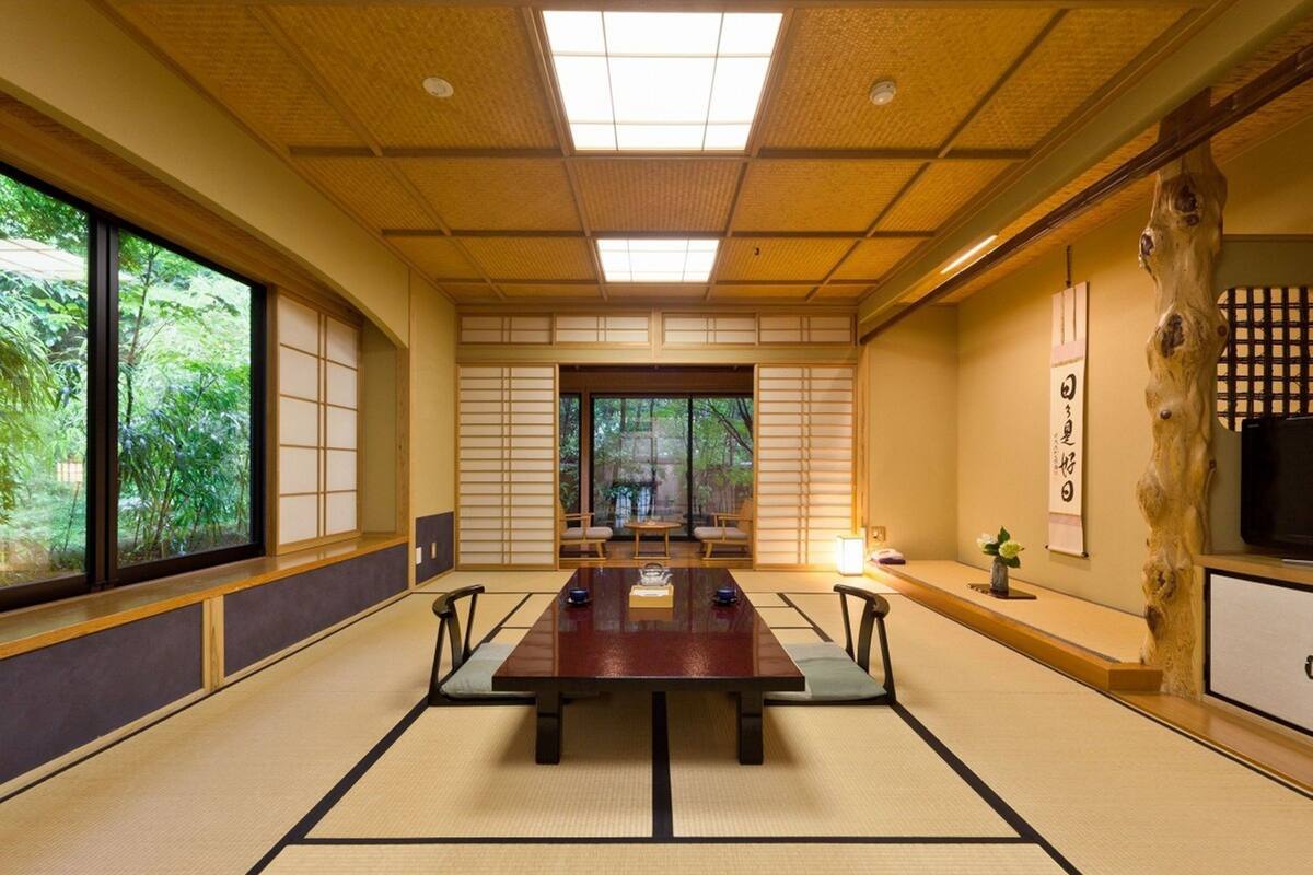 Una habitación japonesa tradicional con suelo de tatami, una mesa baja y puertas correderas.