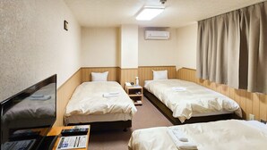 Une chambre d’hôtel avec deux lits, un bureau avec un ordinateur, une télévision et un appareil de climatisation.