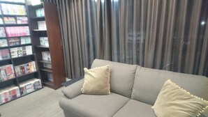 Un salon avec un canapé gris, des coussins beiges et une bibliothèque remplie de livres.