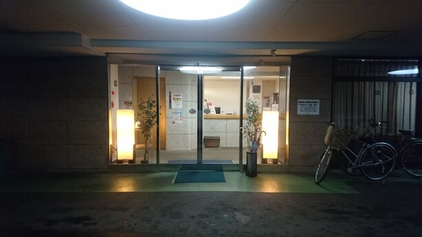 L’entrée d’un hôtel, avec un comptoir d’accueil, un espace d’attente doté d’un tapis bleu et des vélos garés à l’extérieur.