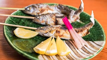 Prato com peixe grelhado, fatias de limão e gengibre em conserva.