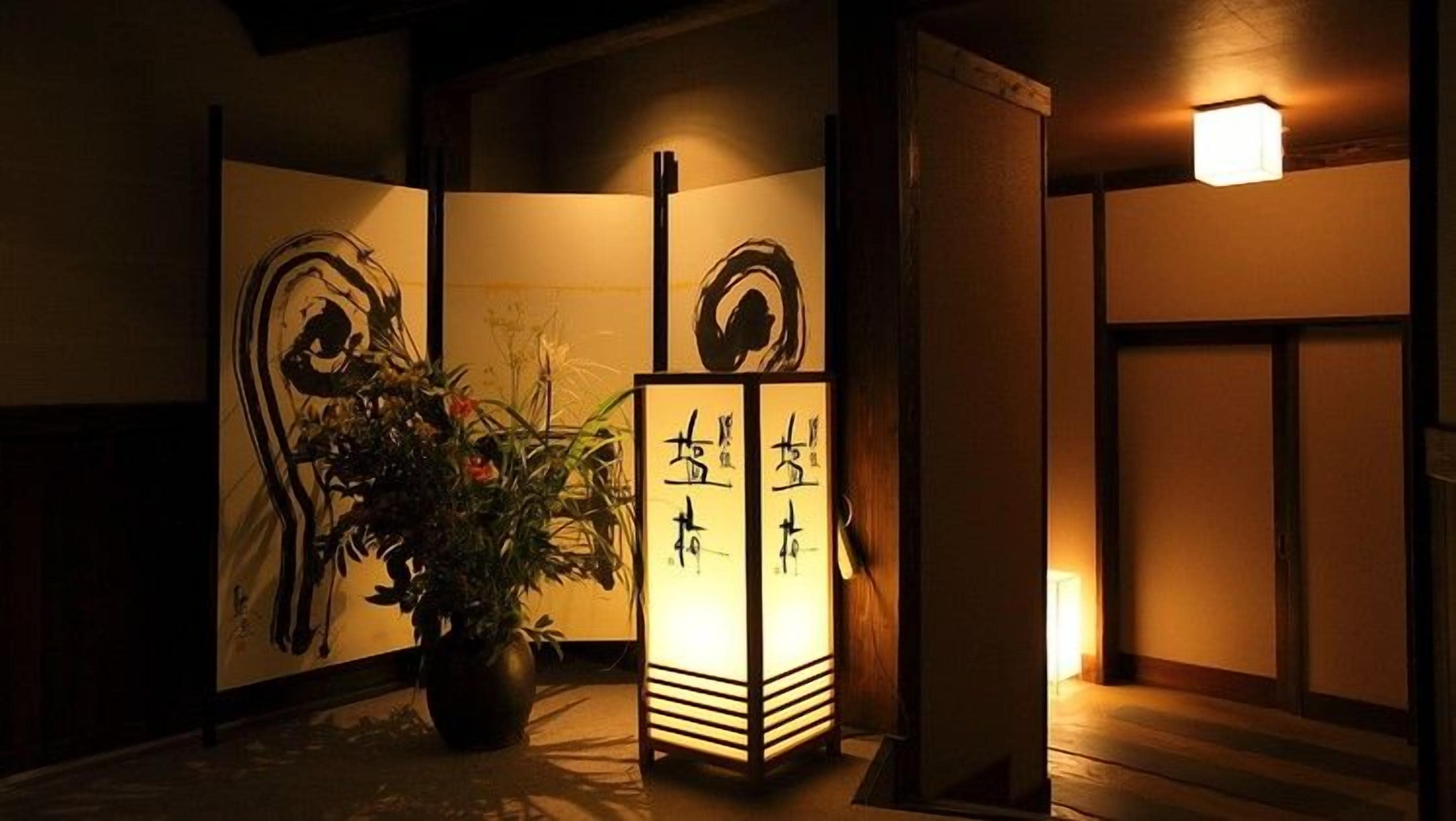 A traditional Japanese room with tatami flooring, a shoji screen with calligraphy, and a lit lantern.