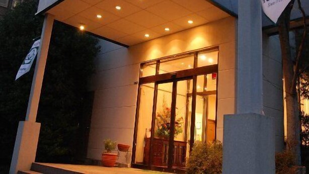 The exterior of the Miss Hotel Tokiwa, featuring a welcoming entrance with a 'Welcome' sign and a logo.