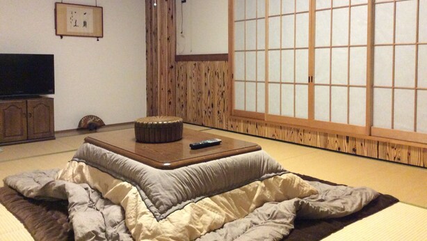 Perinteinen japanilainen huone, jossa on tatamimatto lattialla, matala pöytä, televisio ja liukuvat ovet.