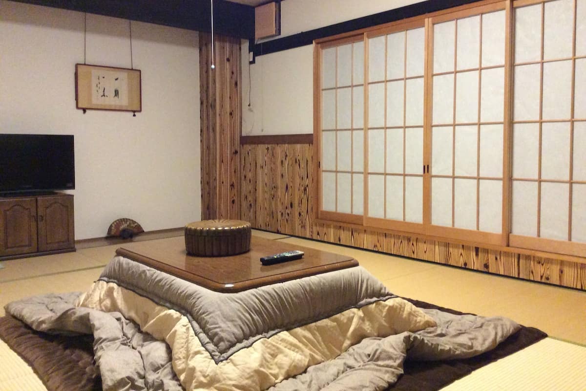 A traditional Japanese tatami mat room with a low table, a television, and sliding doors.