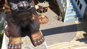 A stone lion statue in a courtyard with a staircase and potted plants. - Surfside Bed & Breakfast (Onna)