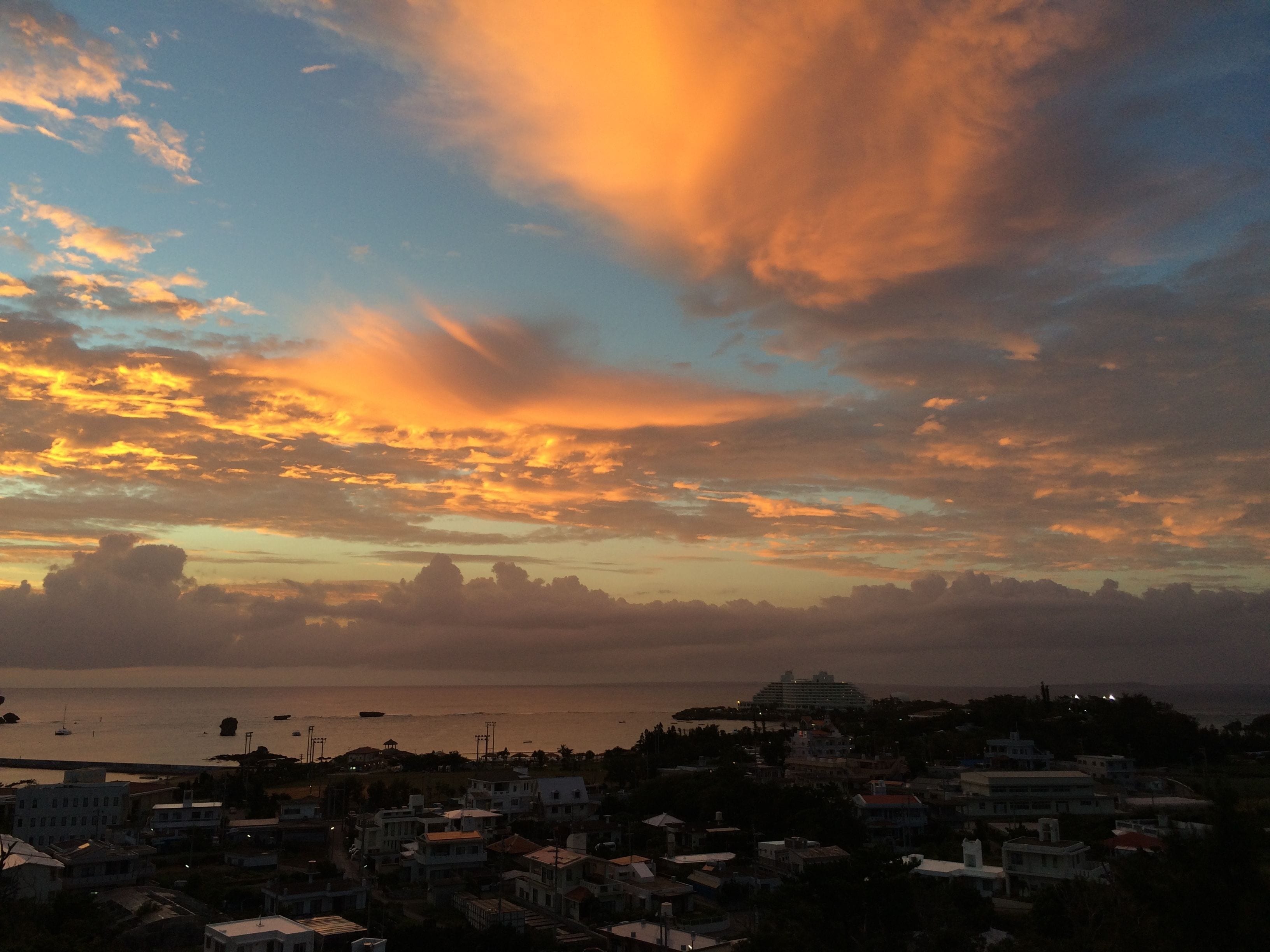 A coastal town at sunset with buildings and a body of water.