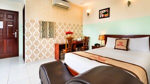 Une chambre d’hôtel équipée d’un lit, d’un bureau, d’une chaise, d’une table de chevet et d’un climatiseur fixé au mur.