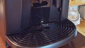 Una cafetera De'Longhi MAGNIFICA negra con un panel de control, una bandeja de goteo y un depósito de agua.