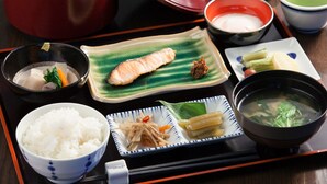 Una comida tradicional japonesa con arroz, salmón y diferentes acompañamientos sobre una bandeja.