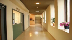 Un pasillo con mostrador de recepción, una escalera y plantas en macetas.