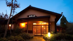 Un edificio tradicional japonés con entrada de madera y un letrero encima.