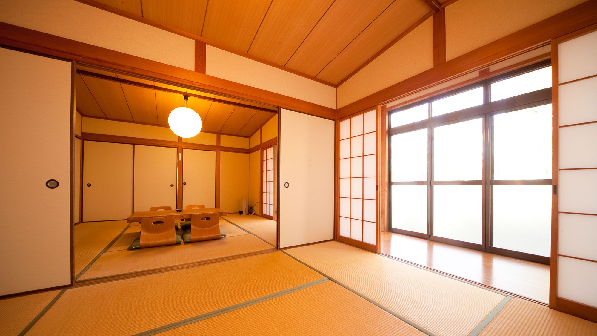 A traditional Japanese room with tatami flooring, sliding doors, and a hanging light fixture.