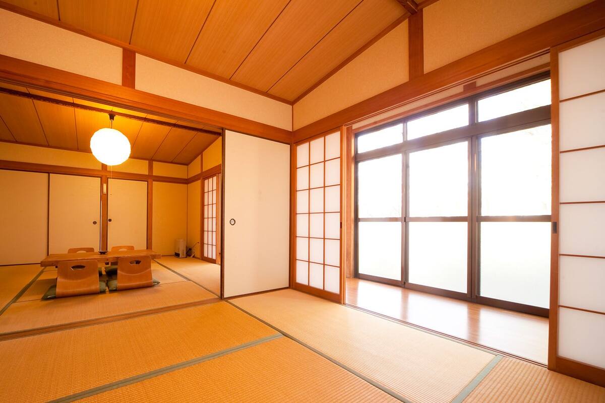 A traditional Japanese room with tatami flooring, sliding doors, and a hanging light fixture.