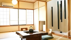 Una habitación tradicional japonesa con suelo de tatami, una mesa de madera baja con un hervidor y puertas correderas.