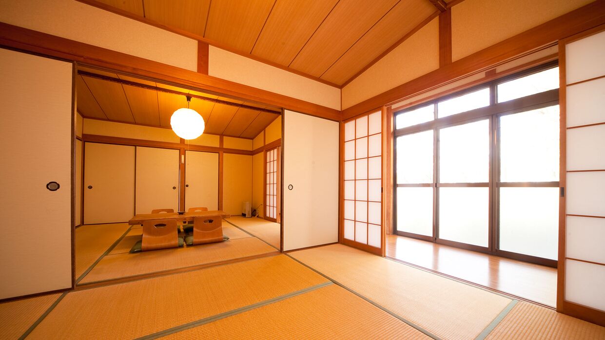 A traditional Japanese room with tatami flooring, sliding doors, and a hanging light fixture.