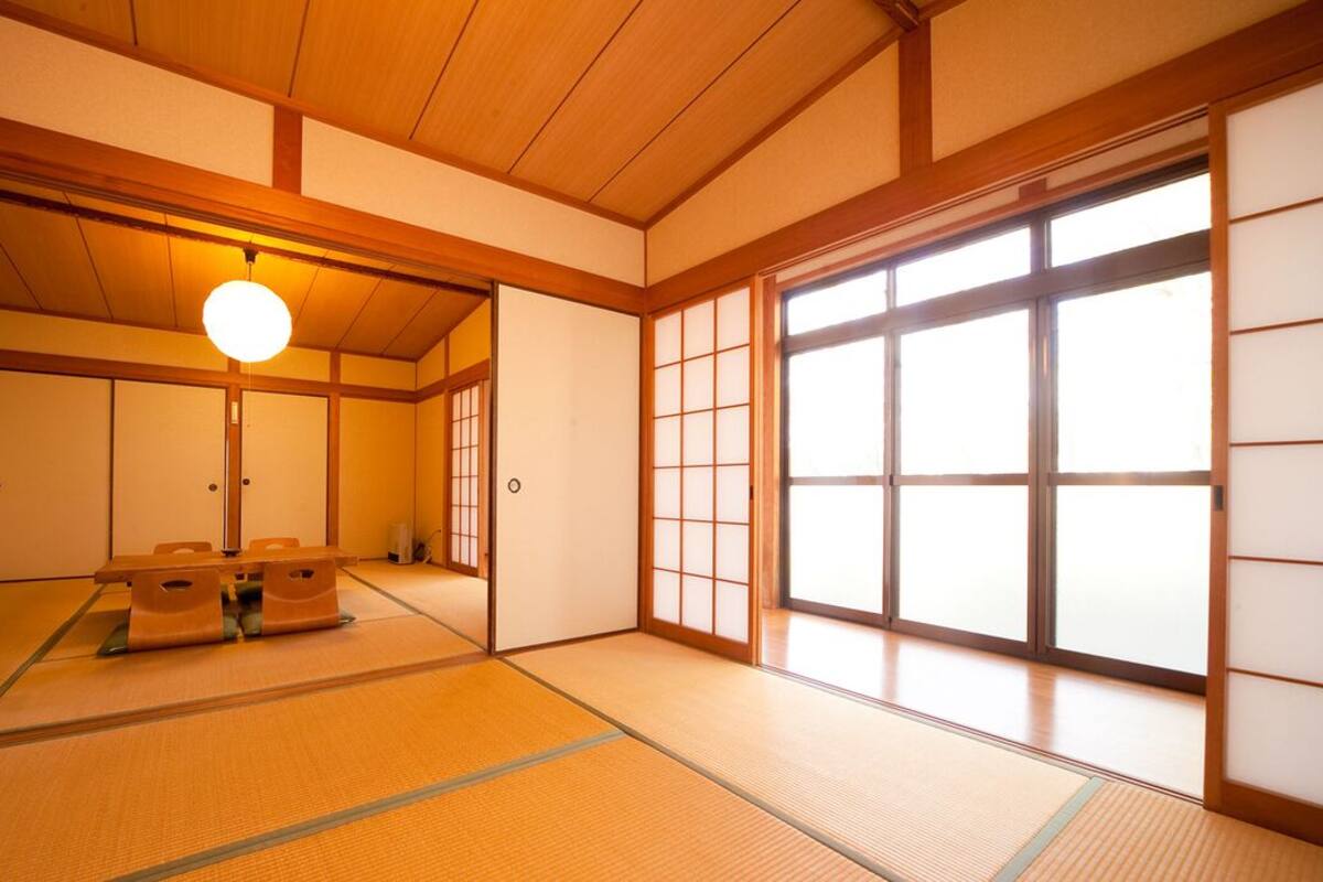 A traditional Japanese room with tatami flooring, sliding doors, and a hanging light fixture.