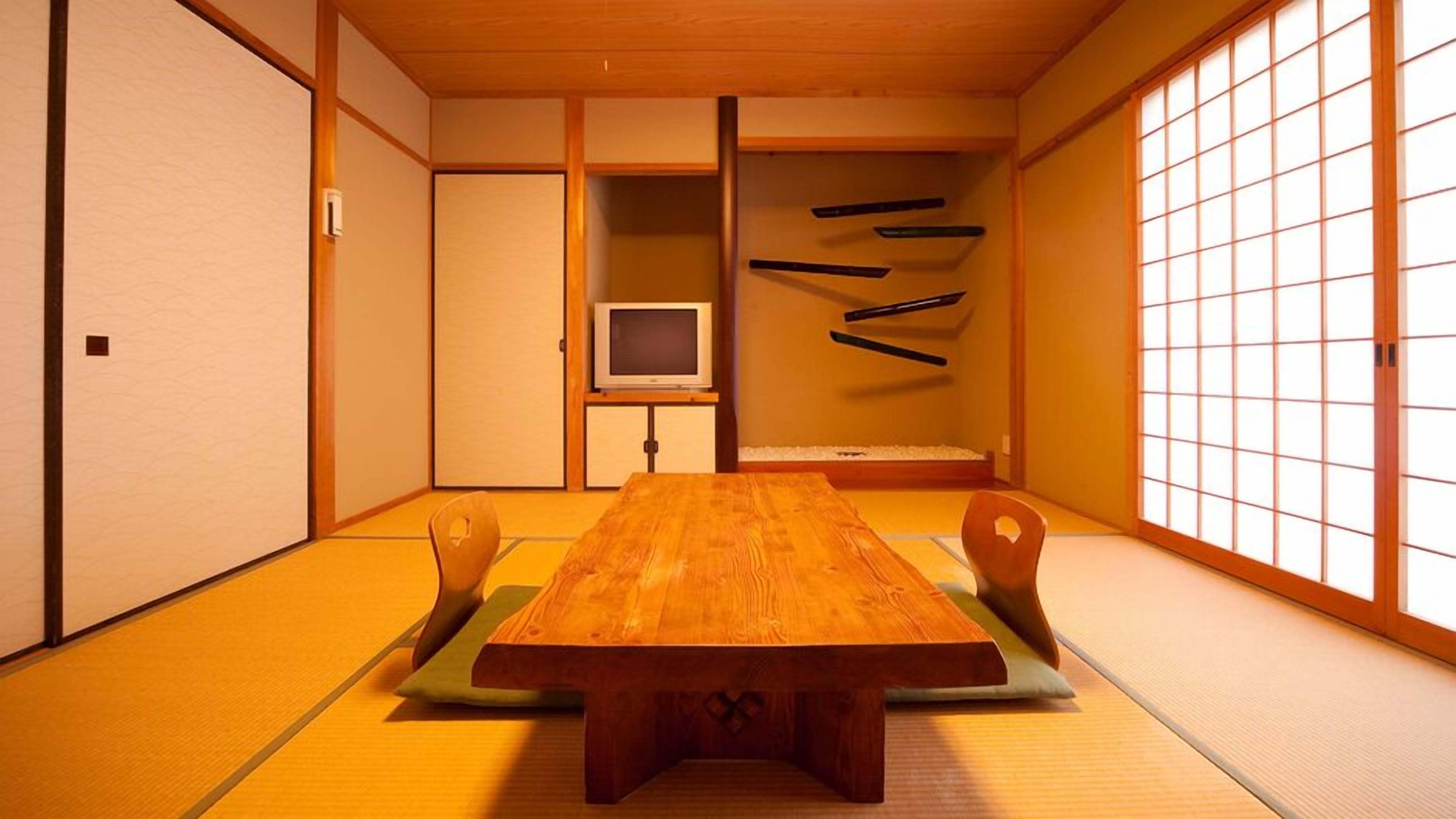 A traditional Japanese room with tatami flooring, a wooden table, and a television.