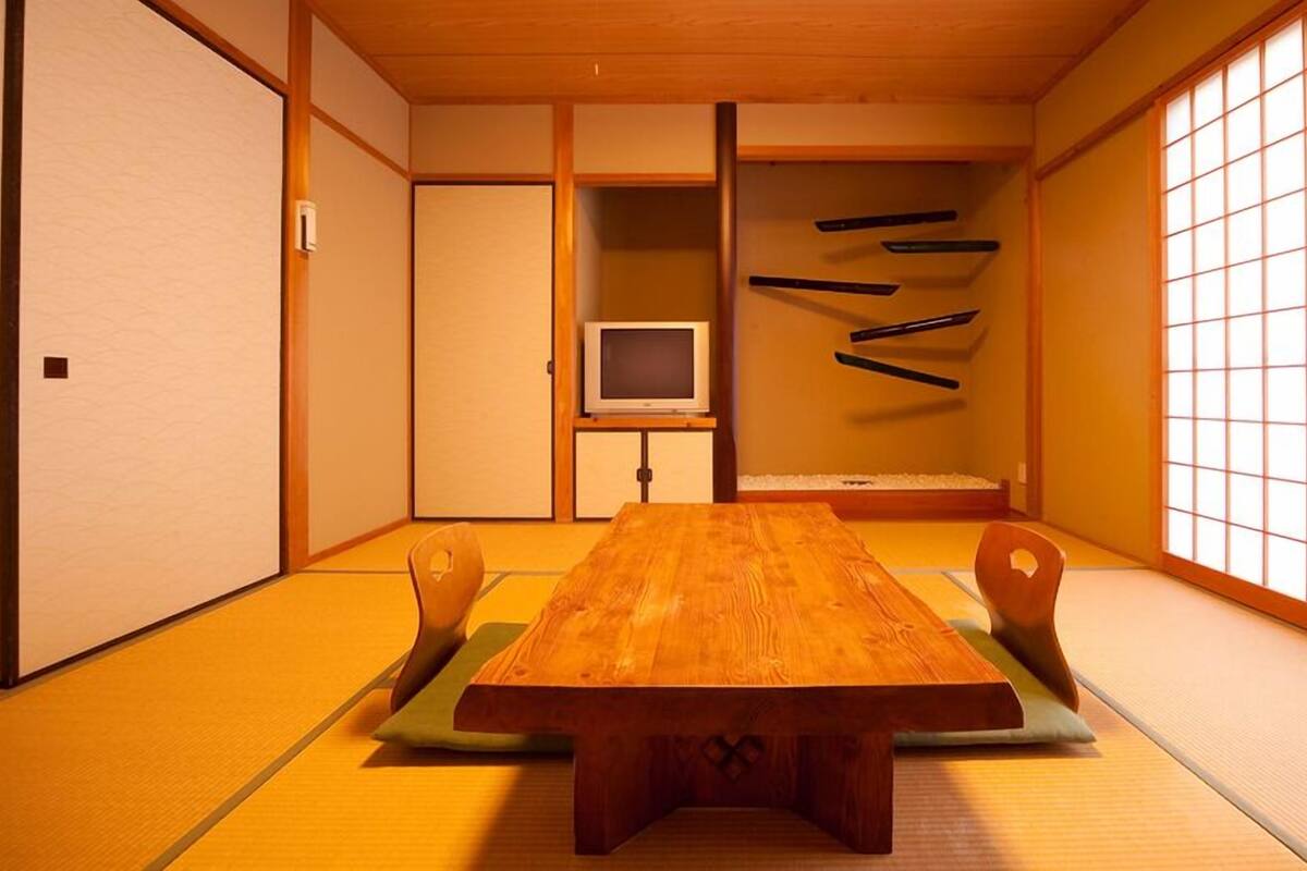 A traditional Japanese room with tatami flooring, a wooden table, and a television.