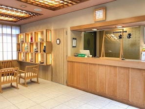 Un espace d’accueil avec des meubles en bois, un comptoir de réception et une horloge au mur.