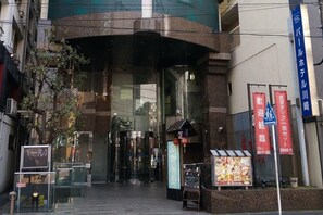 L’entrée d’un hôtel, avec une porte en verre, une enseigne et une banderole rouge.