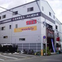 Un edificio de varios pisos con letreros que indican 'BK weekly' y 'Shiohoku'.