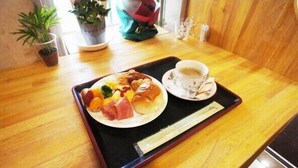 A wooden table with a tray containing a plate of food, a cup of coffee, and chopsticks. - BK Weekly Mansion & Hotel (WAKAYAMA SHI)