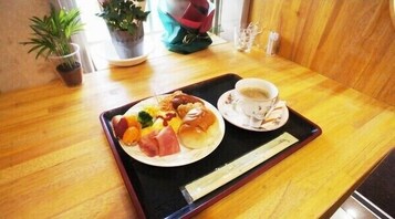 Una mesa de madera con una bandeja que contiene un plato de comida, una taza de café y palillos.
