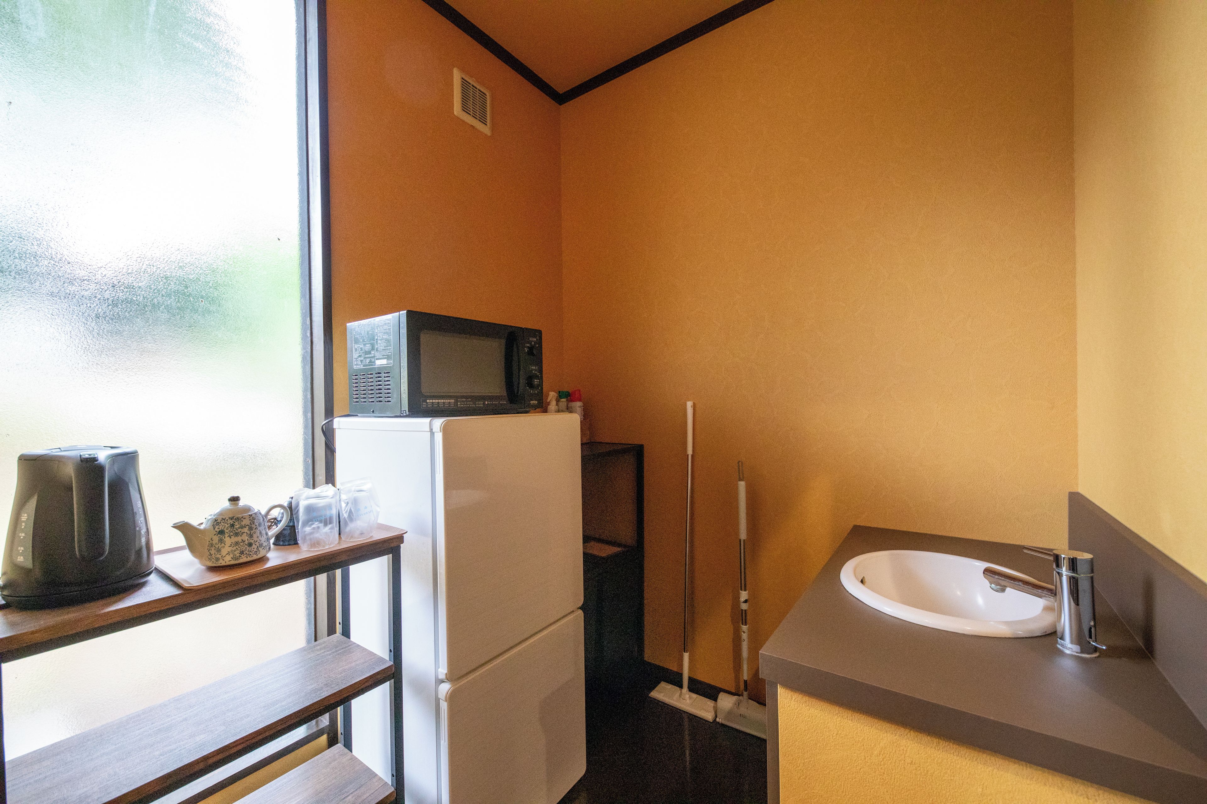 A compact kitchenette with a microwave, refrigerator, and a sink.