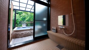 Un baño moderno con un amplio ventanal corredera que da a un balcón, una bañera empotrada y una zona de ducha.